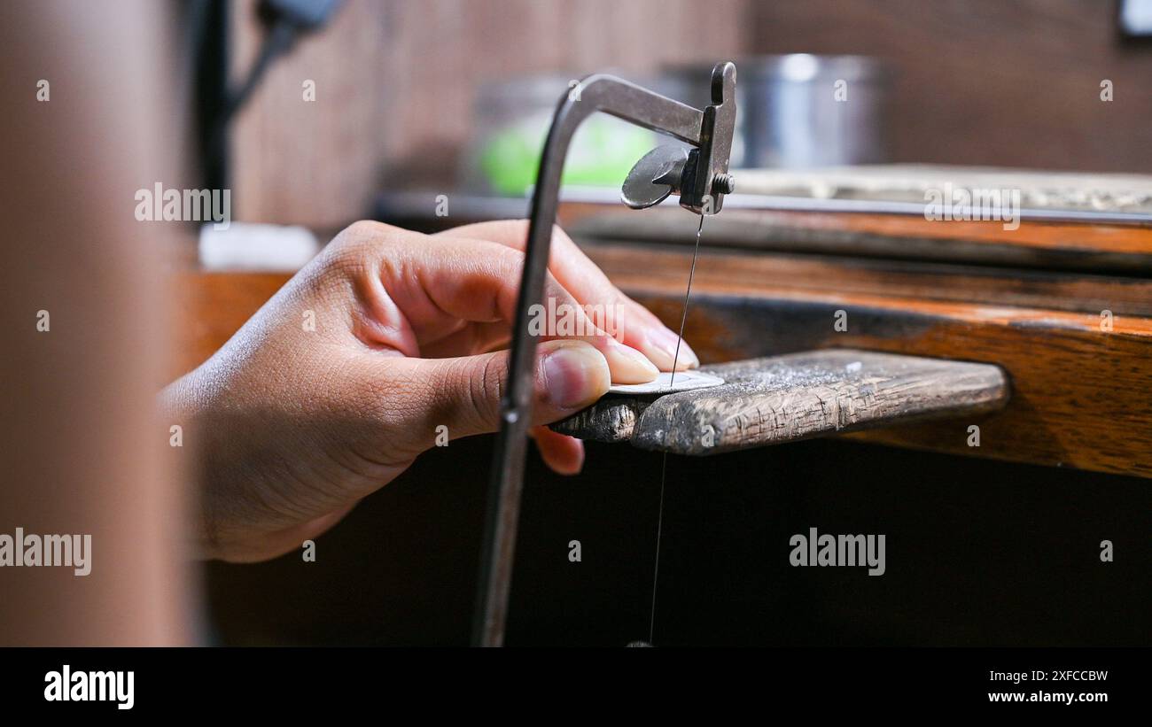 Le mani dell'artigiano modellano meticolosamente un gioiello con gli attrezzi Foto Stock