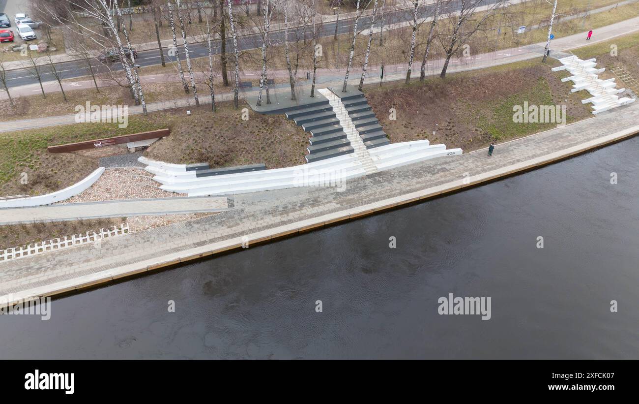 Fotografia con drone di un marciapiede sul fiume in una città durante il giorno nuvoloso primaverile Foto Stock