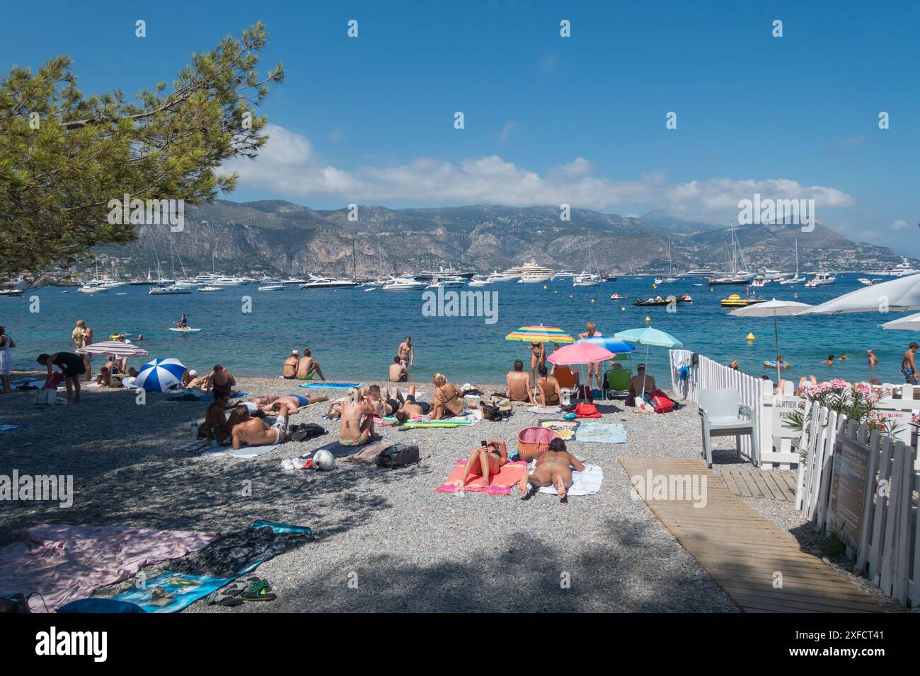 La spiaggia appartata di la Paloma, St-Jean-Cap-Ferrat, sulla Costa Azzurra, con una splendida vista di molti mega yacht di lusso sul Mar Mediterraneo Foto Stock