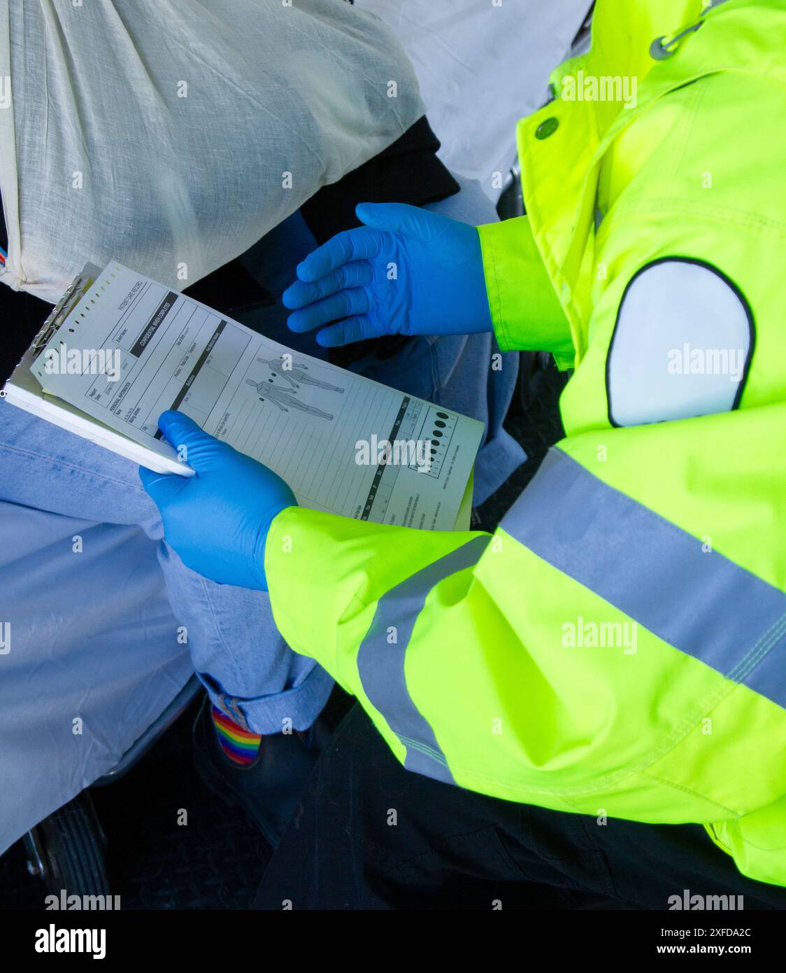 Un paramedico che indossa guanti in lattice trattiene il reddito del paziente durante una dimostrazione di pronto soccorso. Foto Stock