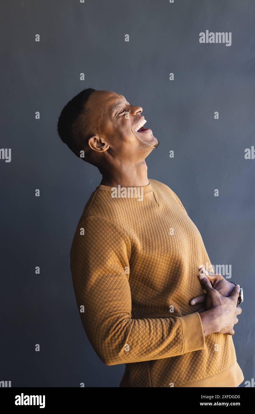 Ridendo con gioia, l'uomo in un maglione casual che si gode un momento di leggerezza Foto Stock Ridendo con gioia, l'uomo in un maglione casual che si gode un momento di leggerezza Foto Stock