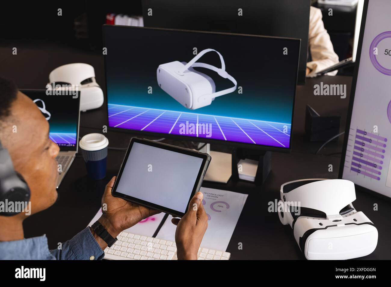 Utilizzando un tablet e indossando le cuffie, l'uomo che lavora con il visore VR e gli schermi, copia spazio Foto Stock