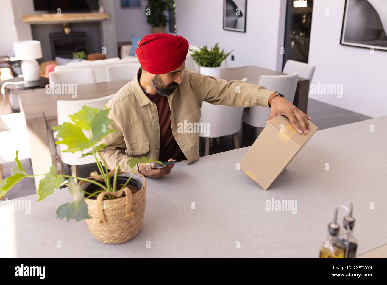 Utilizzando un taglierino, un'apertura di un pacchetto uomo in una moderna cucina domestica Foto Stock