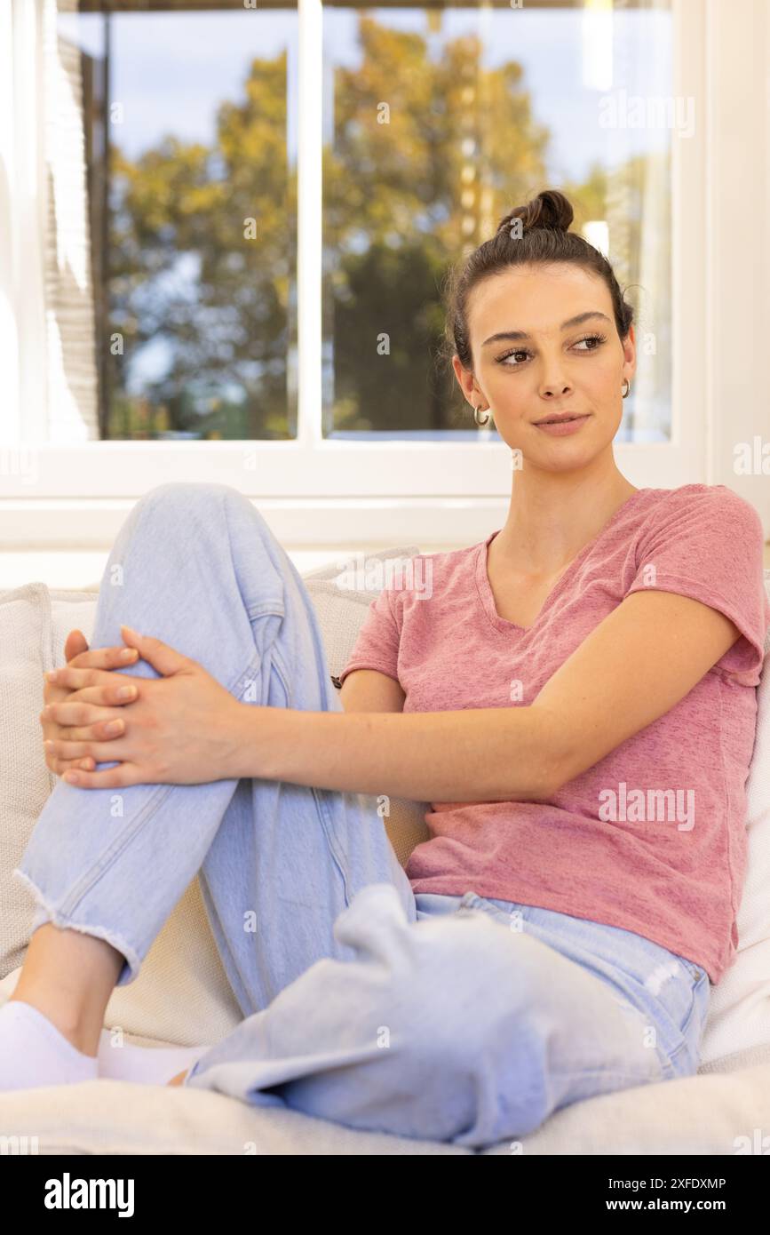 Rilassatevi sul divano, giovani donne in abiti casual che si godono momenti tranquilli Foto Stock Rilassatevi sul divano, giovani donne in abiti casual che si godono momenti tranquilli Foto Stock