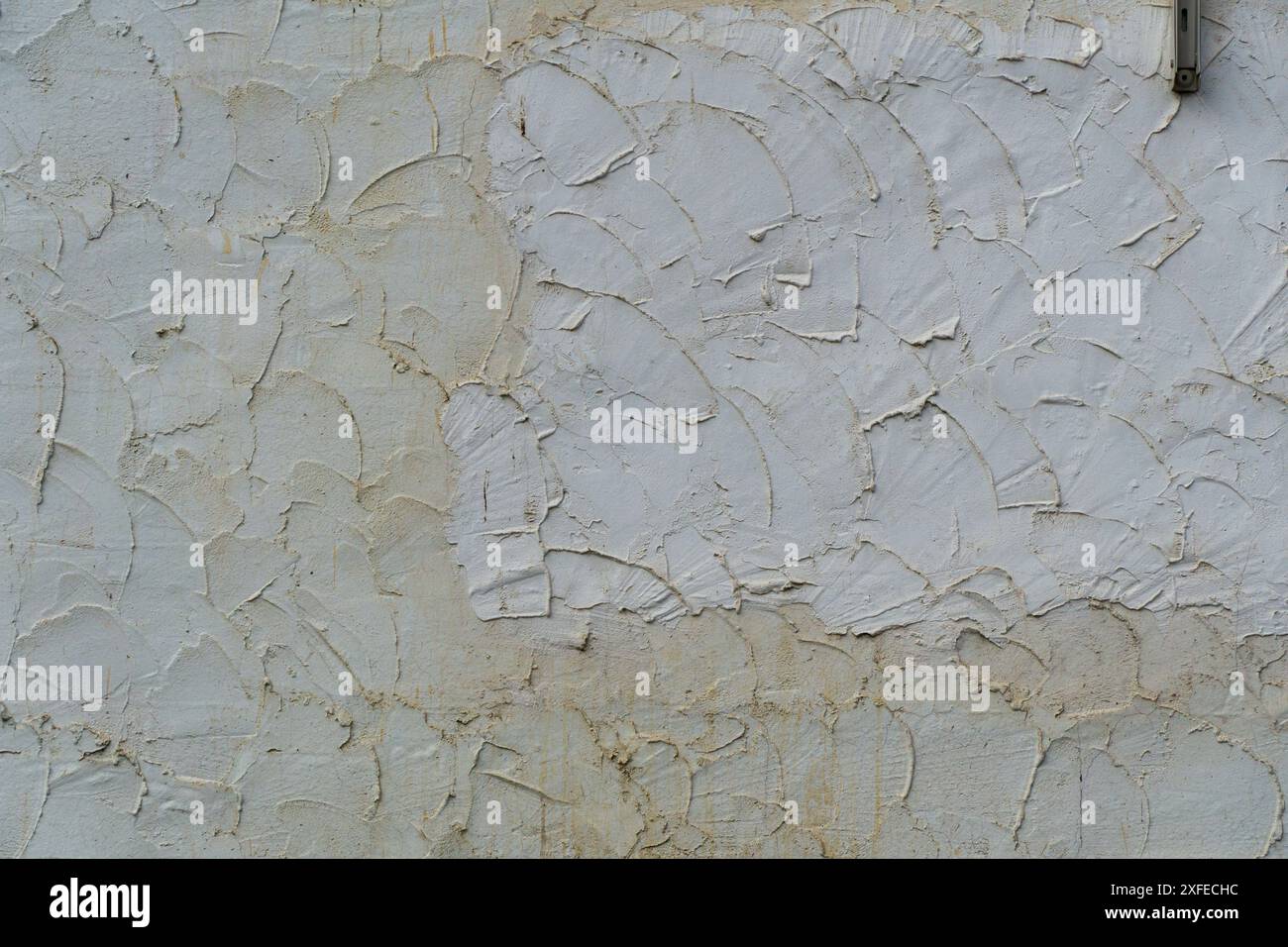 La parete esterna bianca spessa con un rendering a schema approssimativo che mostra segni di cazzuola Foto Stock