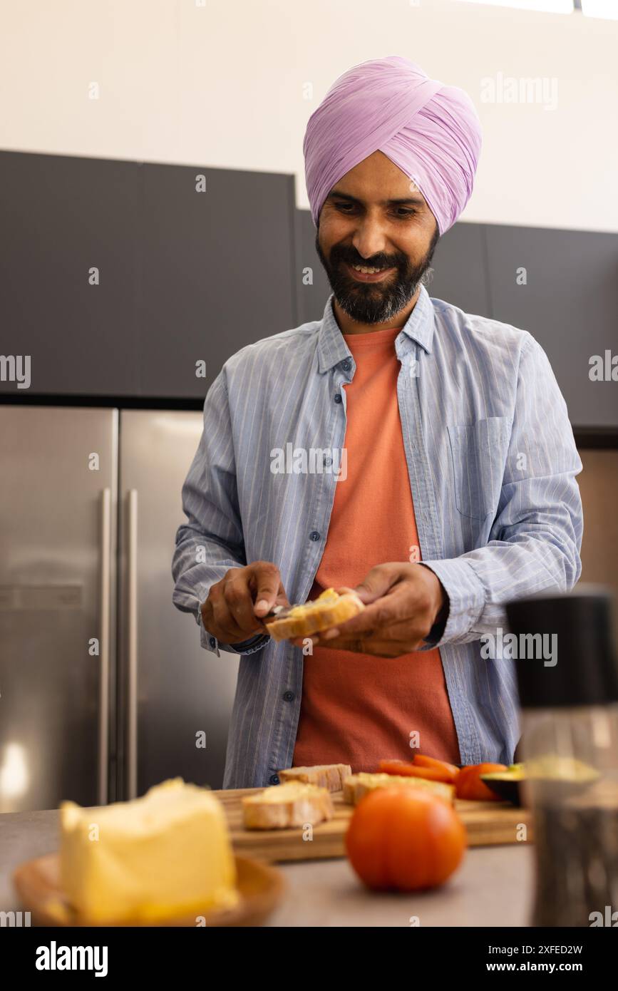 Spalmare burro sul pane, uomo che prepara la colazione in cucina moderna Foto Stock