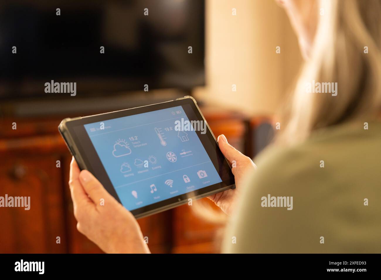 Utilizza un tablet per controllare i dispositivi domestici intelligenti, donna che gestisce l'automazione domestica Foto Stock