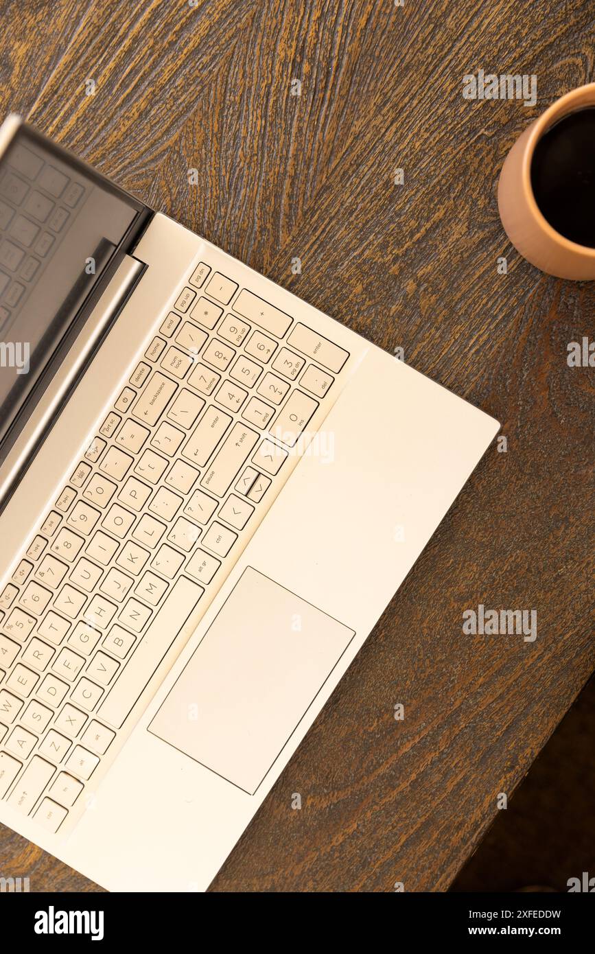 Computer portatile su una scrivania in legno con tazza di caffè, per lavorare da casa Foto Stock