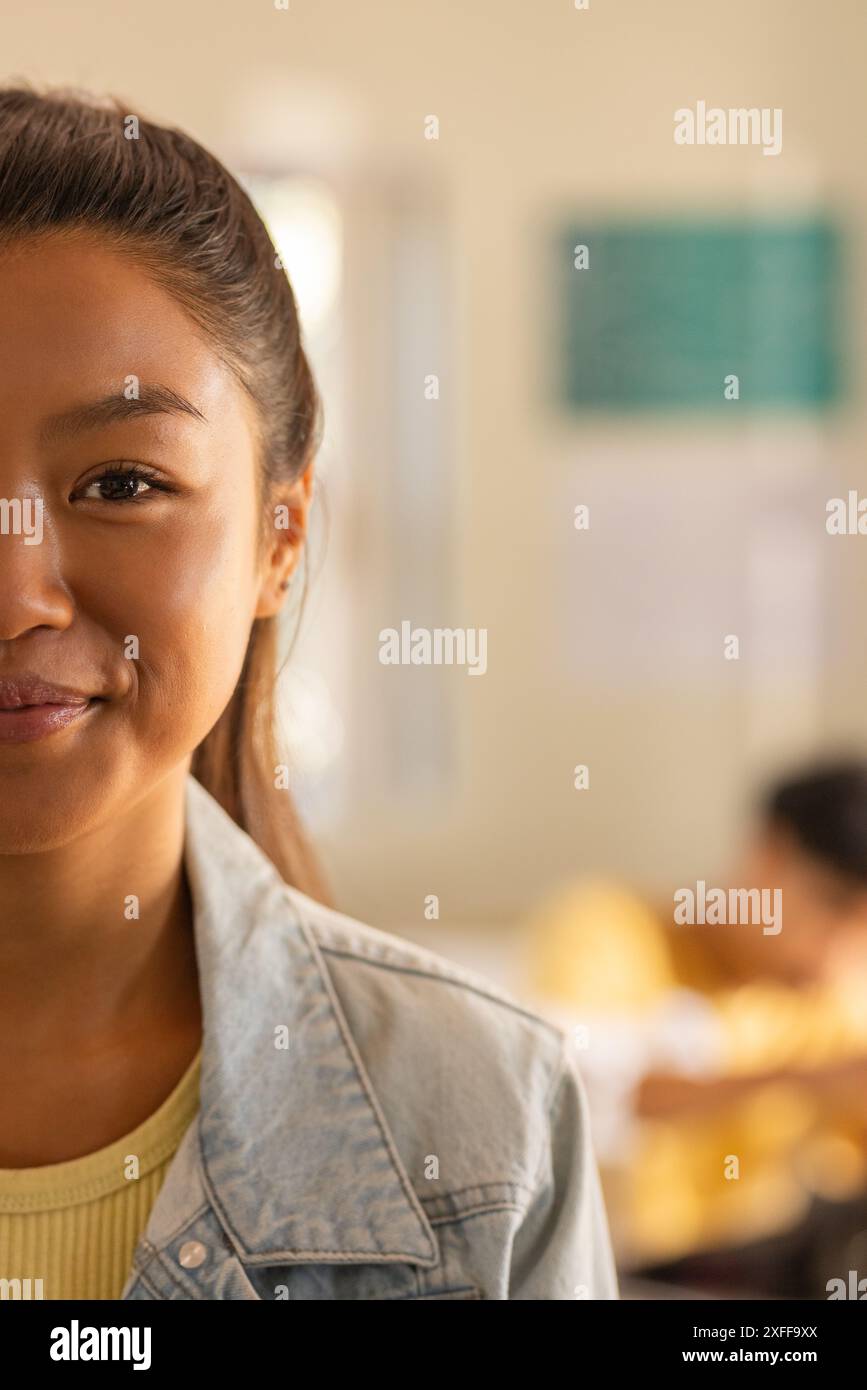 Adolescente sorridente in classe liceale con studentessa che studia in background, copia spazio Foto Stock