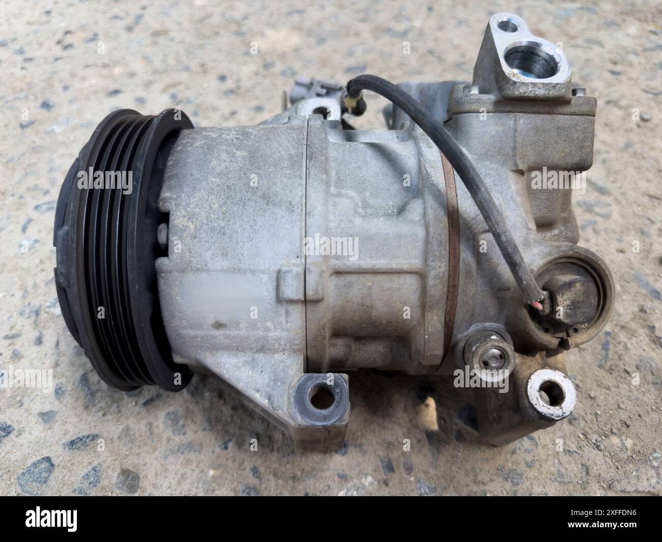 Vista ravvicinata del compressore dell'aria condizionata per uso automobilistico a terra Foto Stock