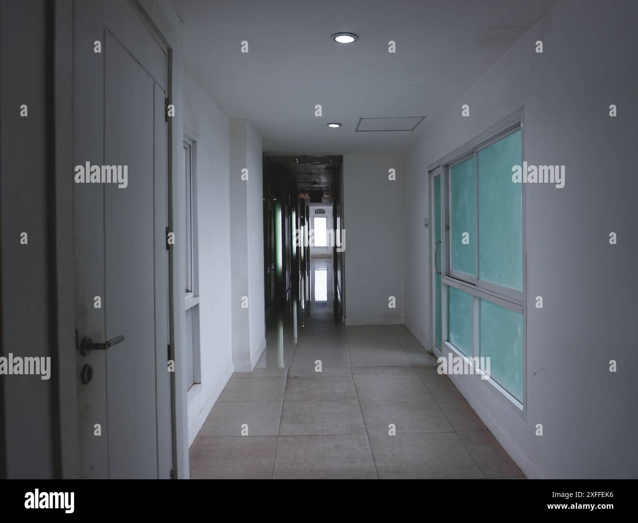 Corridoio all'interno dell'hotel con luce soffusa per entrare nelle camere, con luce che scorre attraverso le finestre. Foto Stock