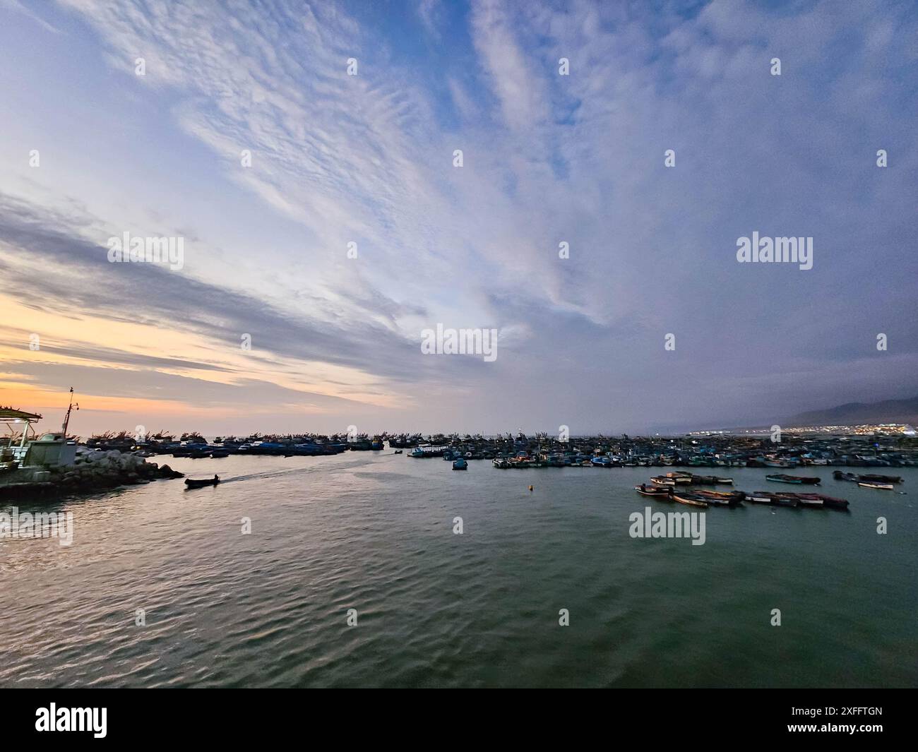 Porto marittimo con molte barche e navi, con vista sul porto al tramonto. Foto Stock