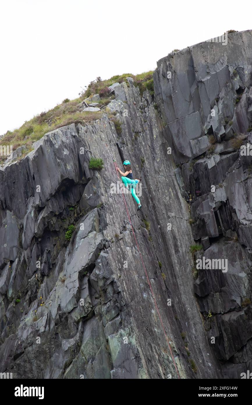 Arrampicata femminile che completa una salita su Fresh Air di grado 6a una pura faccia di ardesia nelle cave di Dinorwig vicino a Llanberis, nel Galles del Nord Foto Stock