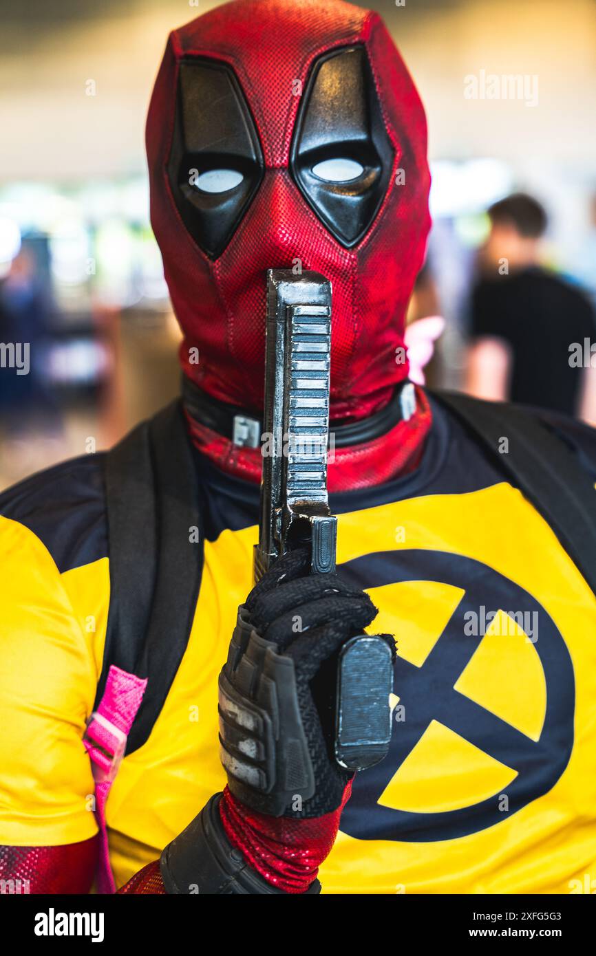 HARROGATE, REGNO UNITO 22 GIUGNO 2024. Primo piano ritratto di un cosplayer maschile vestito da Deadpool e in posa con una pistola e abiti Wolverine Foto Stock