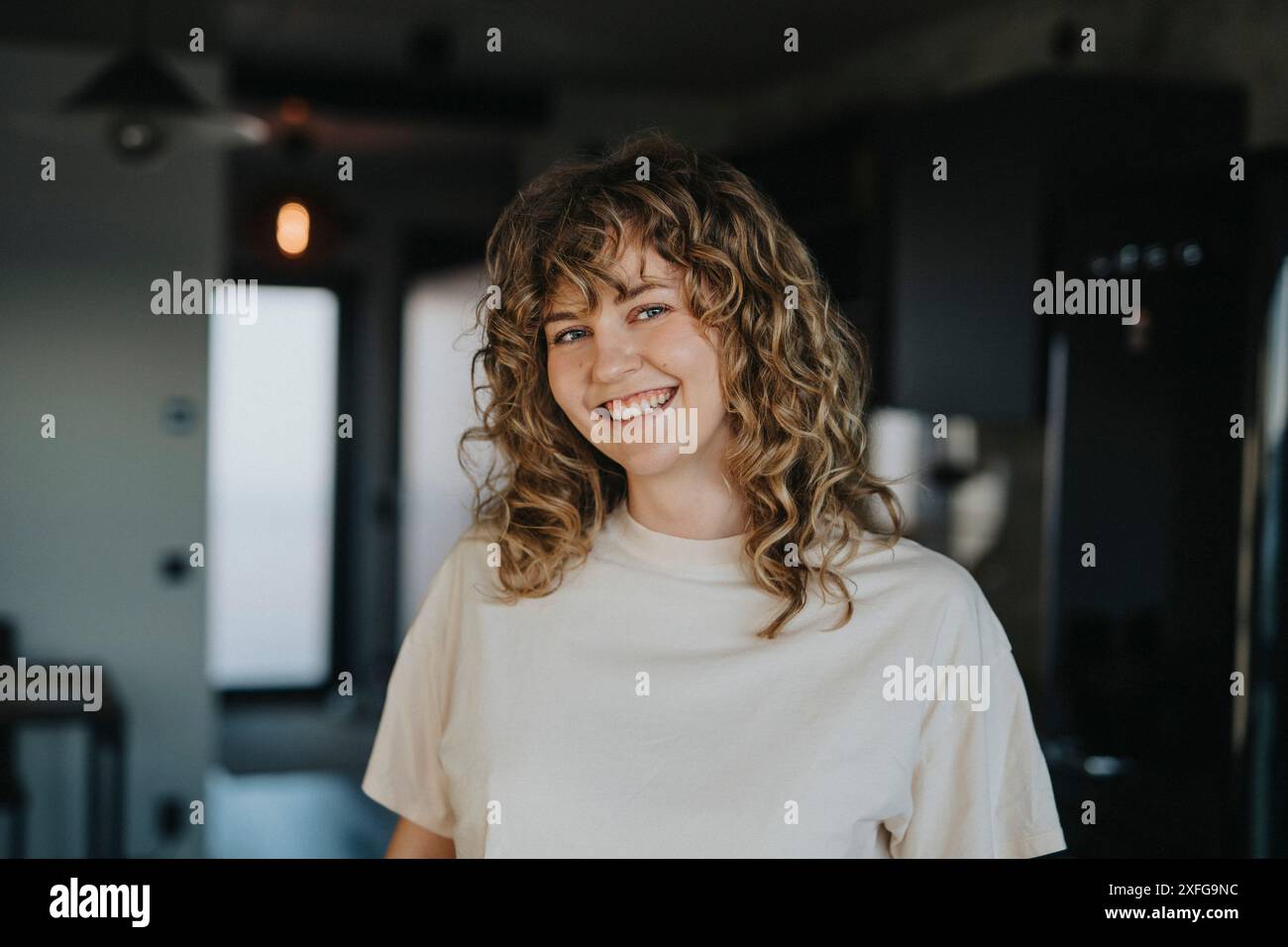 Ritratto di una bella donna felice con i capelli ricci a casa Foto Stock