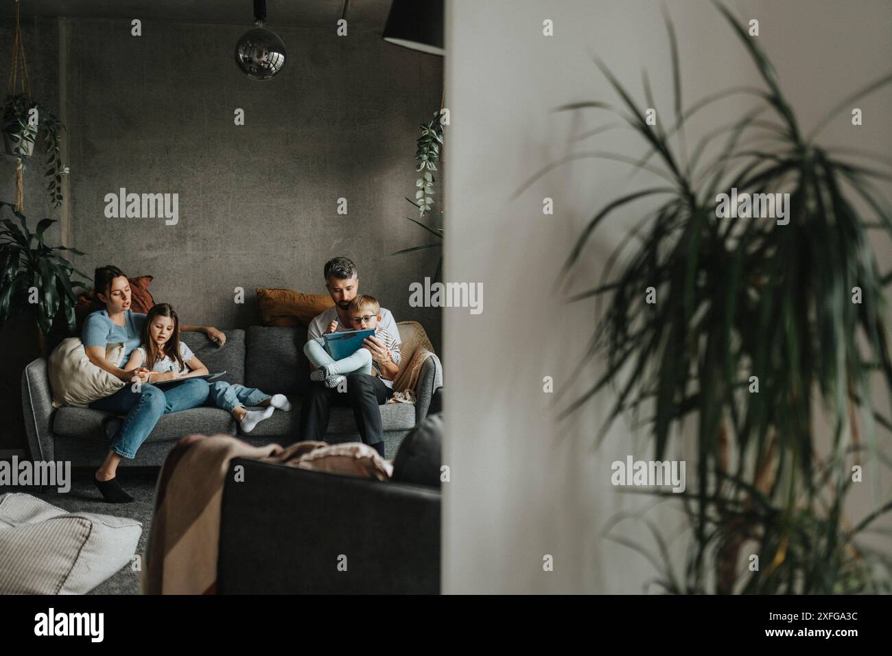 Genitori concentrati che studiano a casa figlio e figlia seduti sul divano di casa Foto Stock