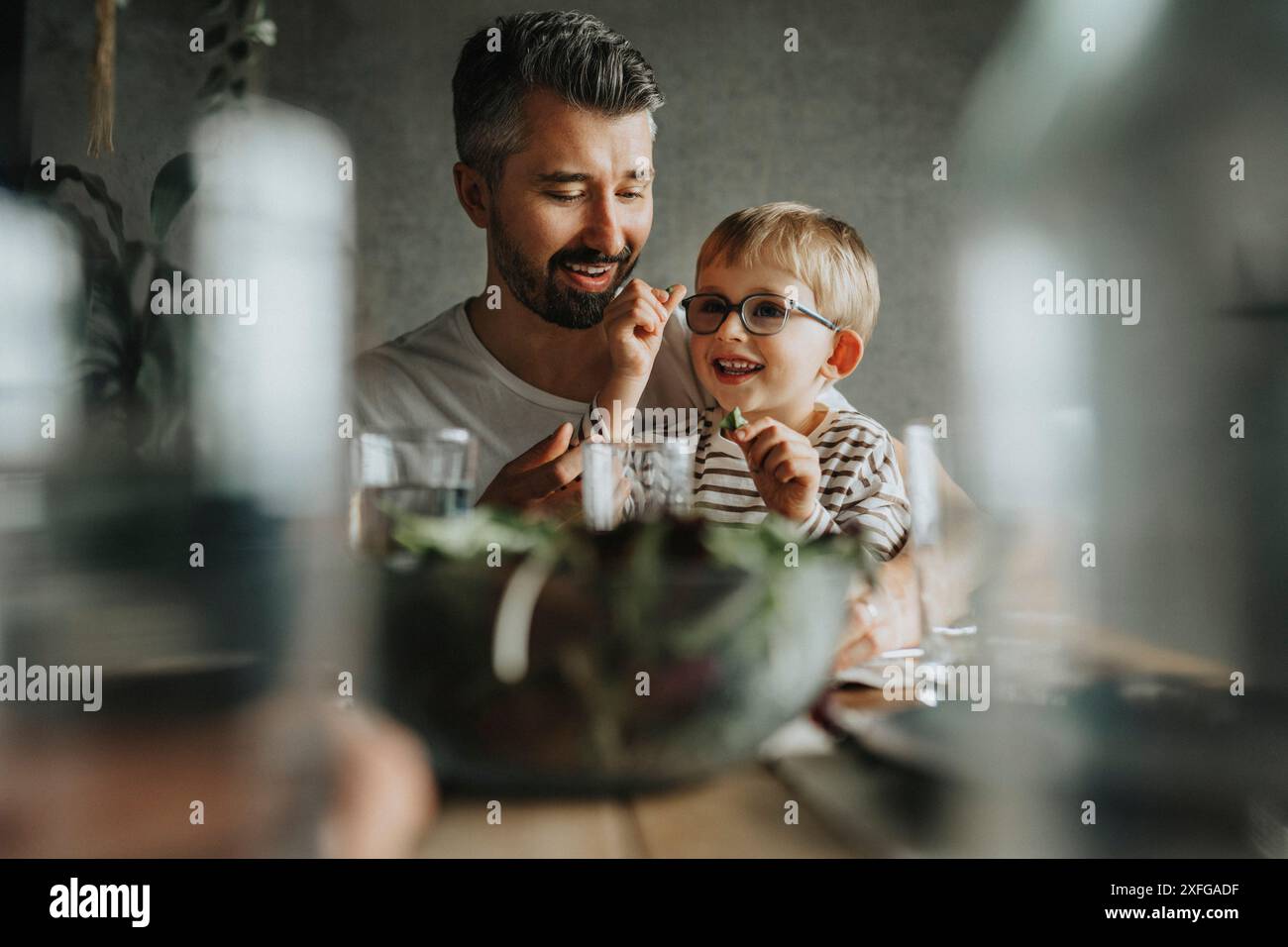 Padre e figlio felici che mangiano a tavola Foto Stock