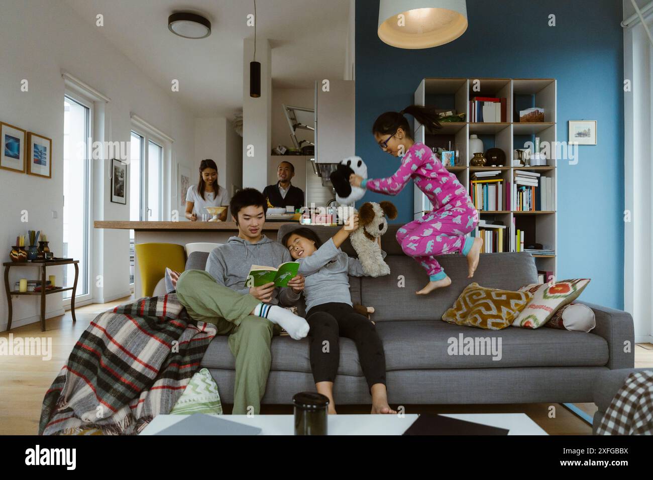 Fratelli che si divertono mentre giocano sul divano nel soggiorno di casa Foto Stock