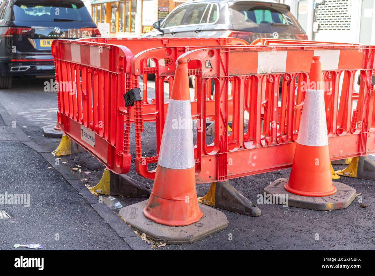 Piccole quantità di lavori stradali con barriere e coni in una strada principale. Foto Stock