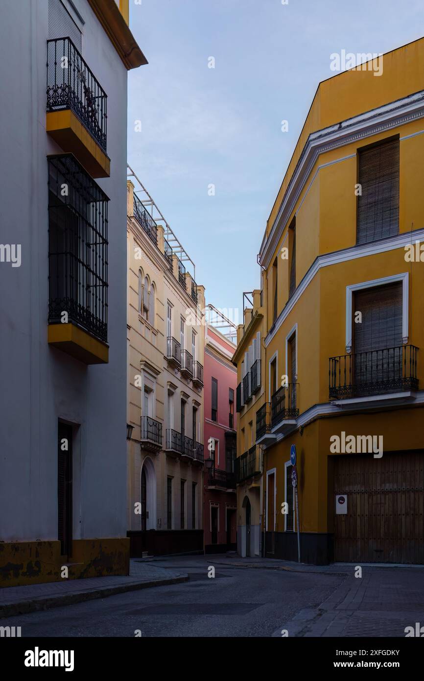 Strada stretta e vuota con edifici colorati e balconi a Siviglia, Spagna Foto Stock