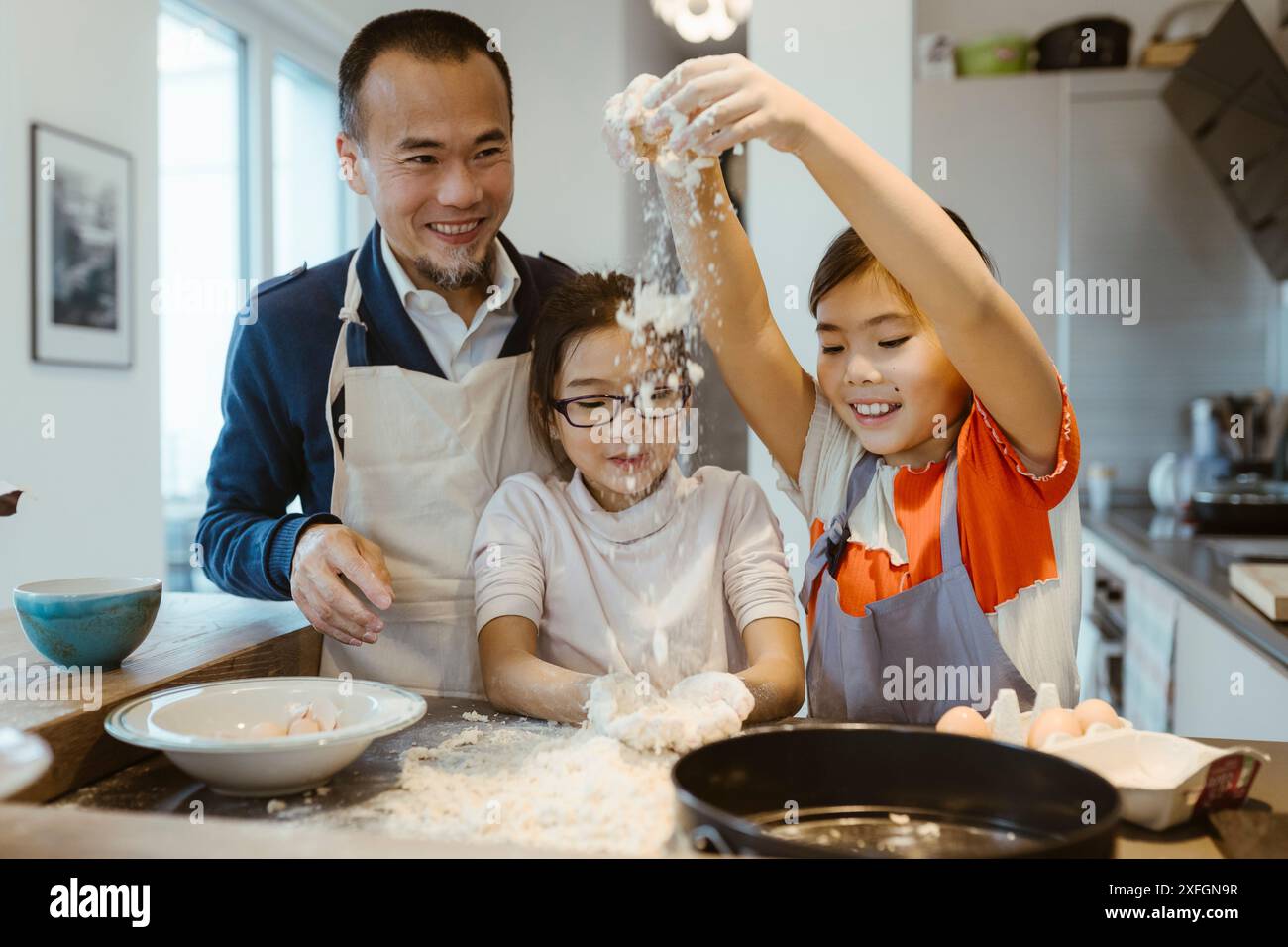 Le figlie si divertono a giocare con l'impasto mentre cuocono con il padre a casa Foto Stock