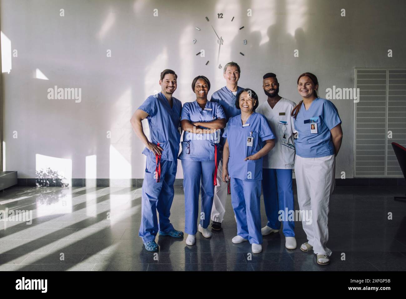 Ritratto di uomini felici e donne esperti medici in piedi insieme davanti all'ospedale Foto Stock