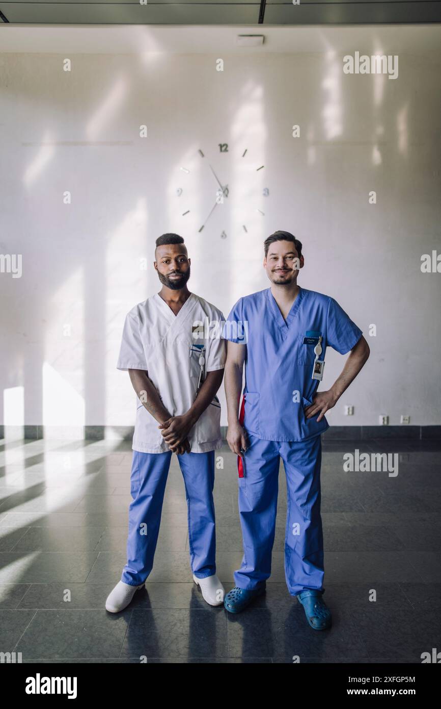 Ritratto di professionisti medici uomini multirazziali in piedi di fronte al muro in ospedale Foto Stock