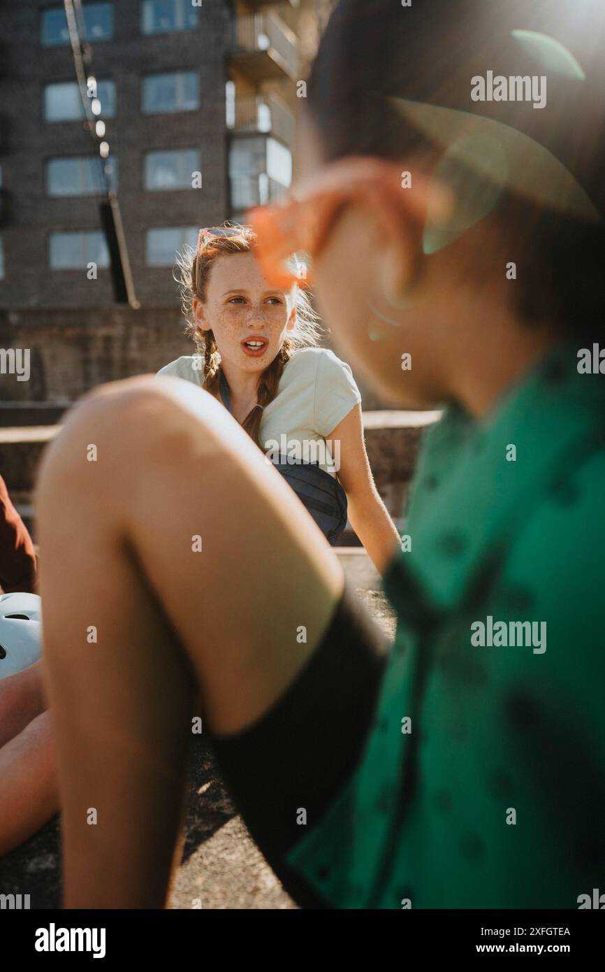 Ragazza seduta con un'amica al giorno di sole Foto Stock