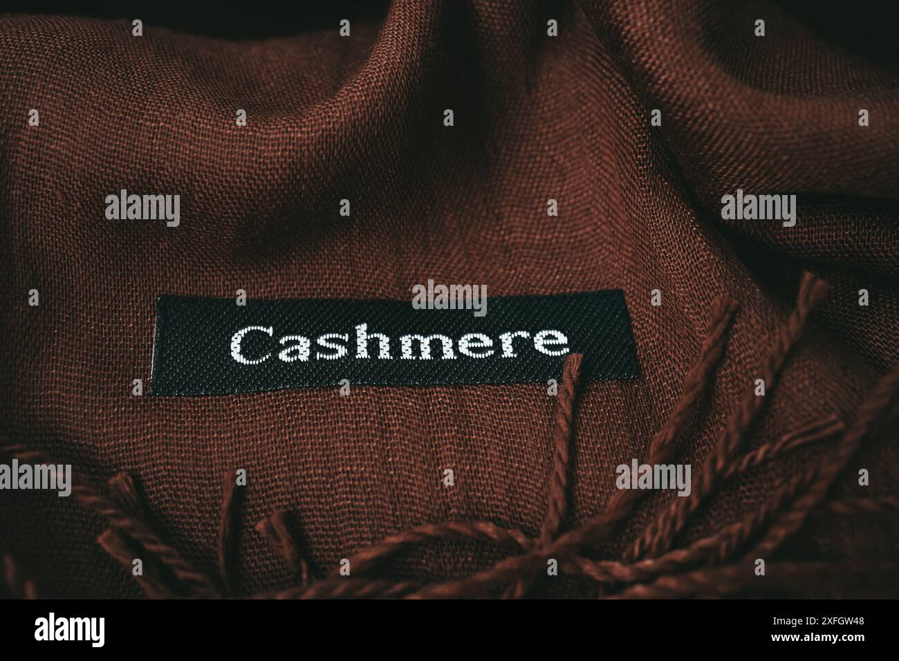 Consistenza in cashmere marrone intenso. Sfondo in tessuto cioccolato. Etichetta in tessuto su sciarpa in cashmere con testo cashmere in lingua inglese materiale Foto Stock