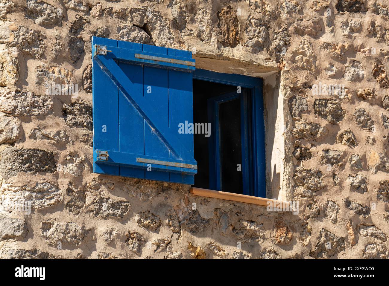 Finestra con persiane in legno blu su una parete in pietra, persiane scure Foto Stock