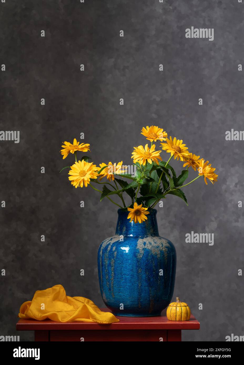 Un bouquet di colori gialli autunnali in un grande vaso blu su sfondo grigio scuro. Calma la natura morta. Rilassati. Colori brillanti. Piacere . Interni di casa. Foto Stock