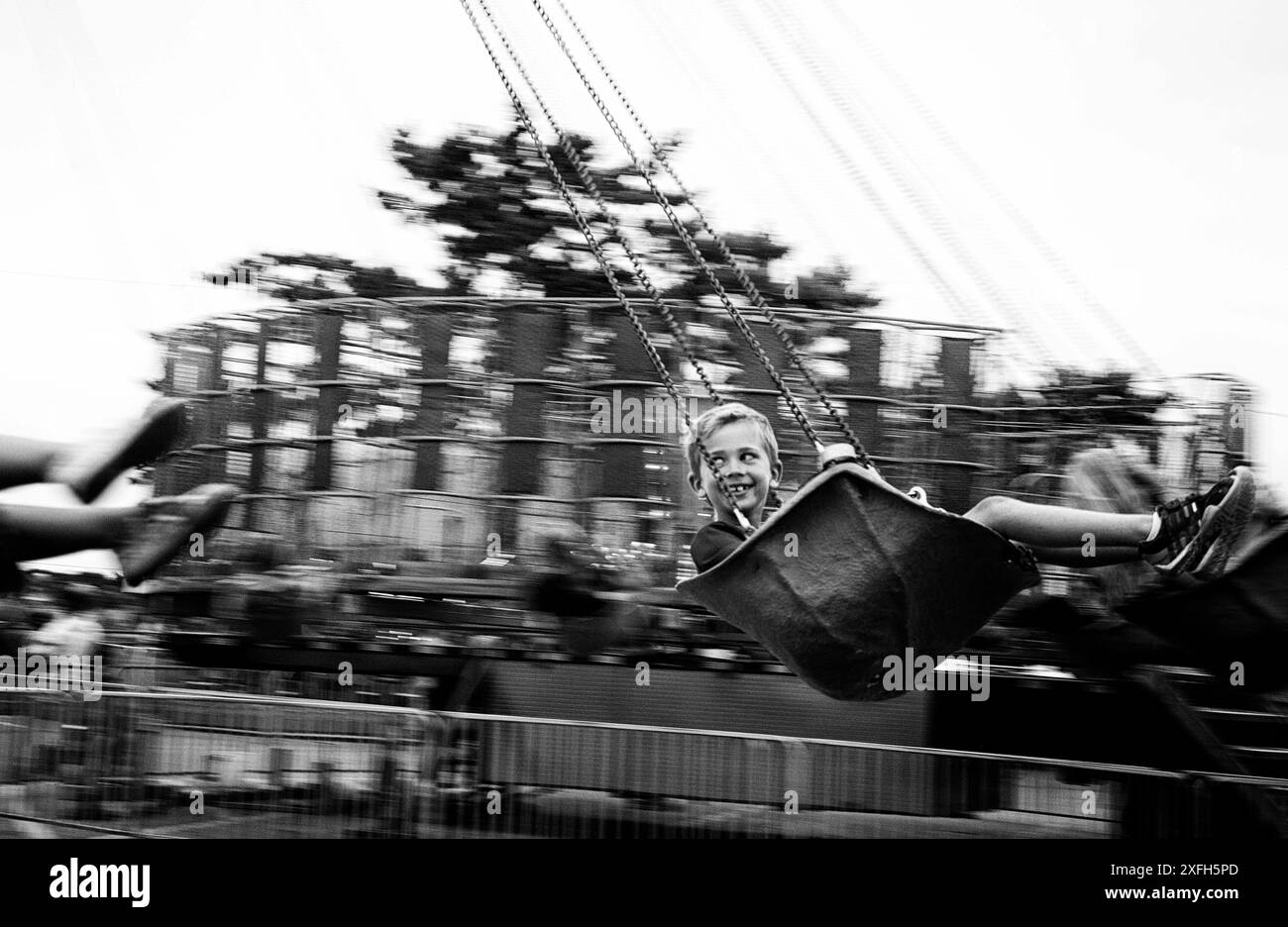 Sorridente ragazzo in altalena al parco divertimenti Foto Stock