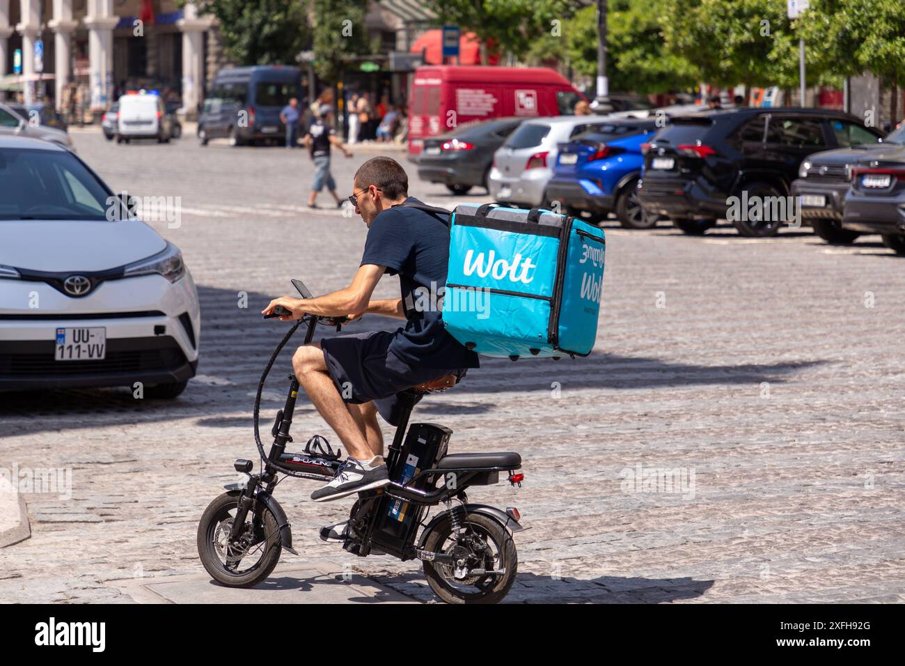 Tbilisi, Georgia - 17 GIUGNO 2024: Corriere Wolt in bicicletta che consegna ordini di cibo online. Wolt è una piattaforma finlandese per la distribuzione di cibo online per il settore alimentare e la distribuzione di cibo Foto Stock