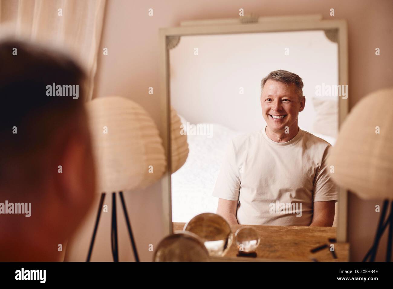 Sorridente uomo maturo seduto davanti allo specchio a casa Foto Stock