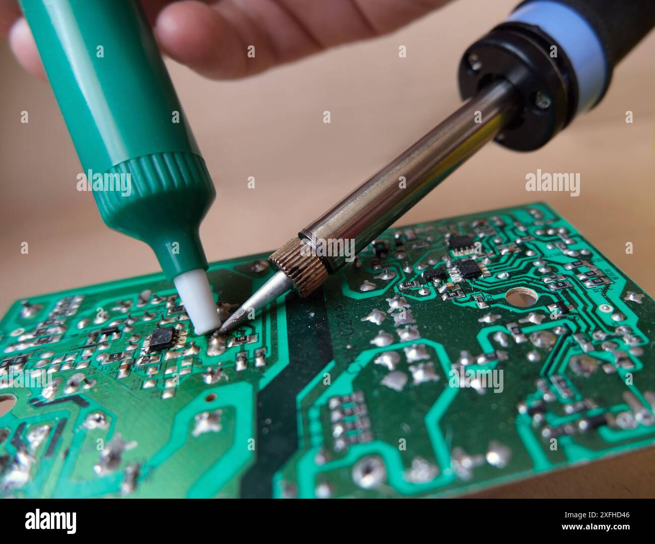 Apparecchiature elettroniche di riparazione per tecnici o riparatori. Lavori di dissaldatura con una pompa e un saldatore. Foto Stock