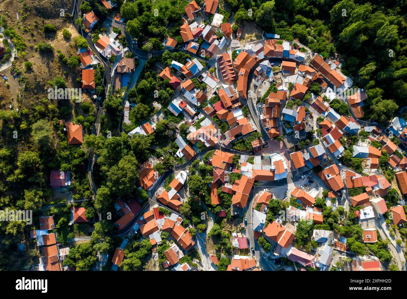 Vista dei droni che mostra le piccole case del villaggio di Foini con tetti rossi nel mezzo della foresta. Distretto di Limassol, Cipro Foto Stock