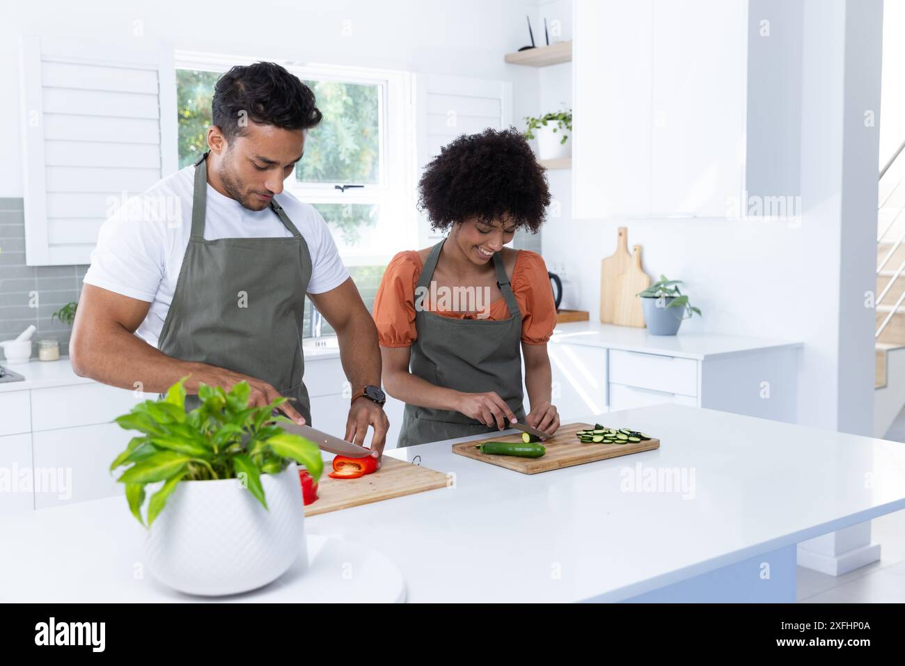 Preparare le verdure, una coppia indossa grembiuli tritare su taglieri in cucina Foto Stock