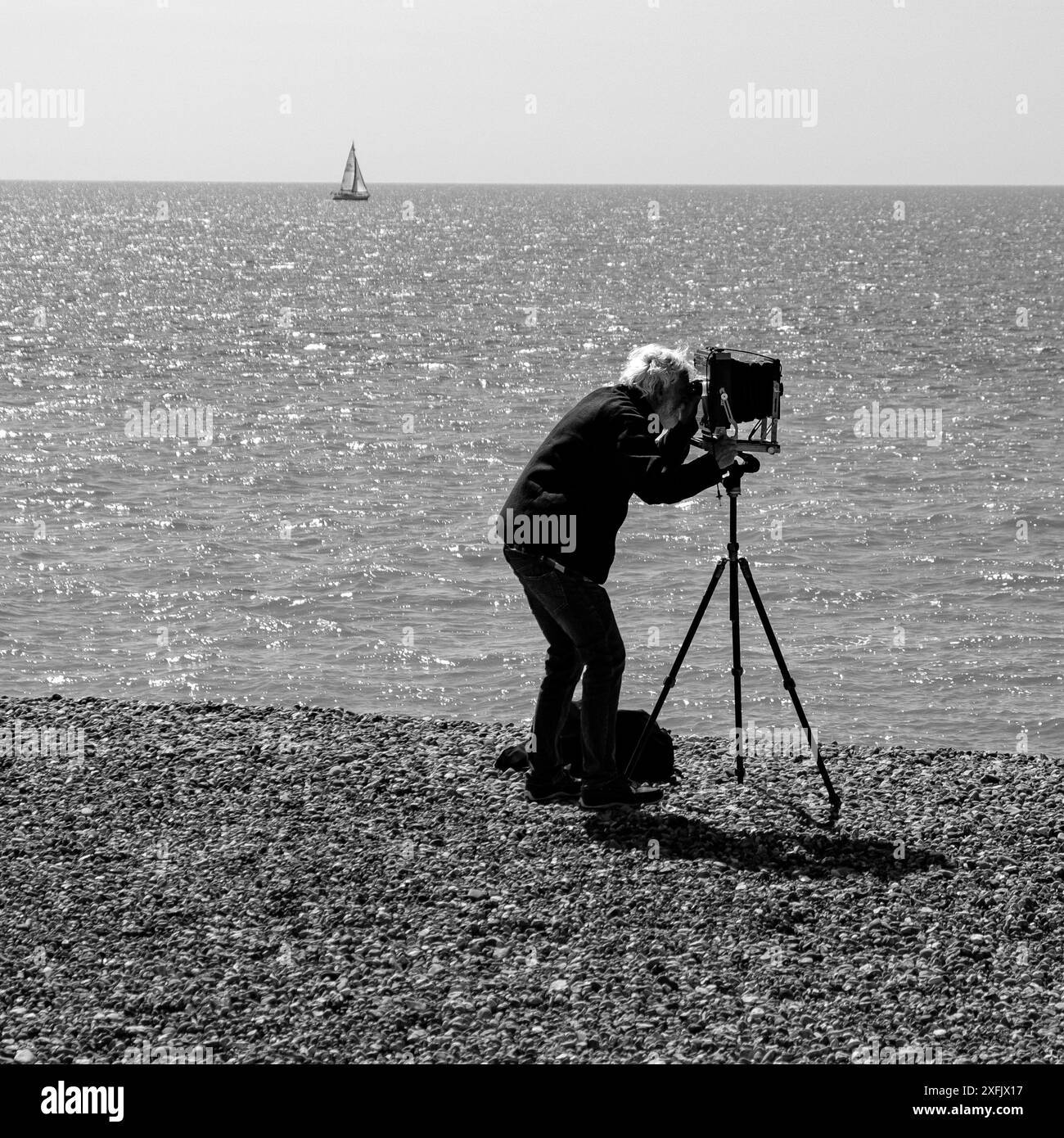 Un fotografo a Eastbourne Beach che scatta una foto con una fotocamera a lastra su un treppiede Foto Stock