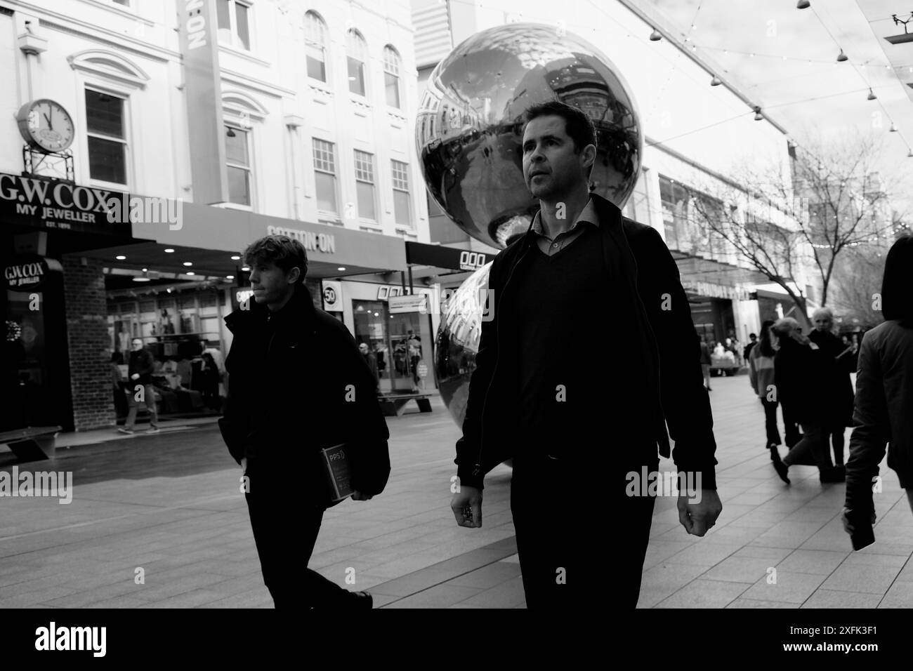 Gruppo di persone che camminano per le strade di fronte a negozi e Street art Foto Stock