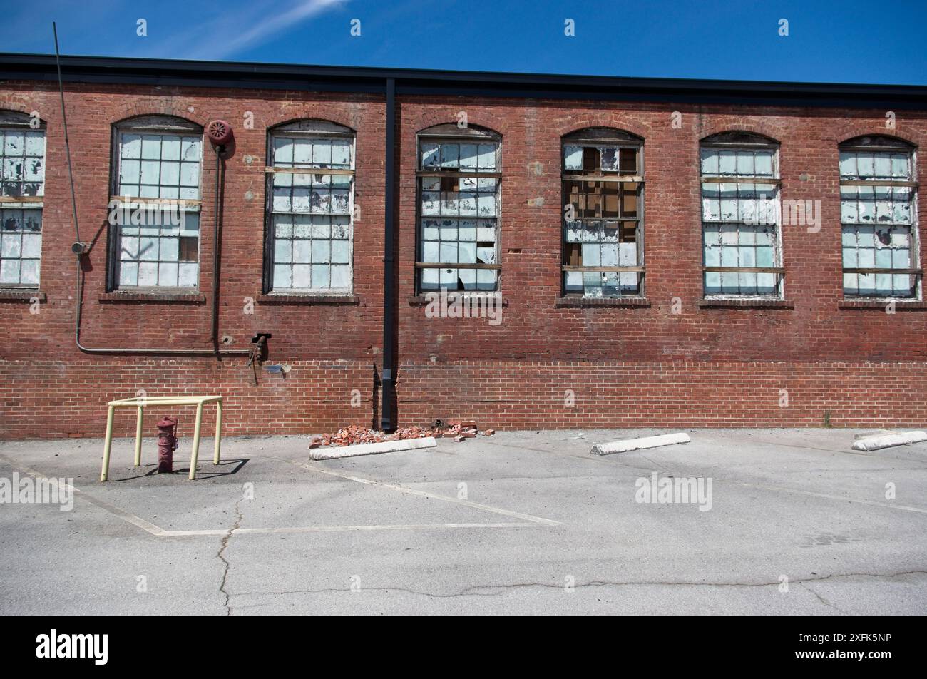 Edificio industriale in mattoni abbandonato con finestre rotte e usurate dalle intemperie Foto Stock