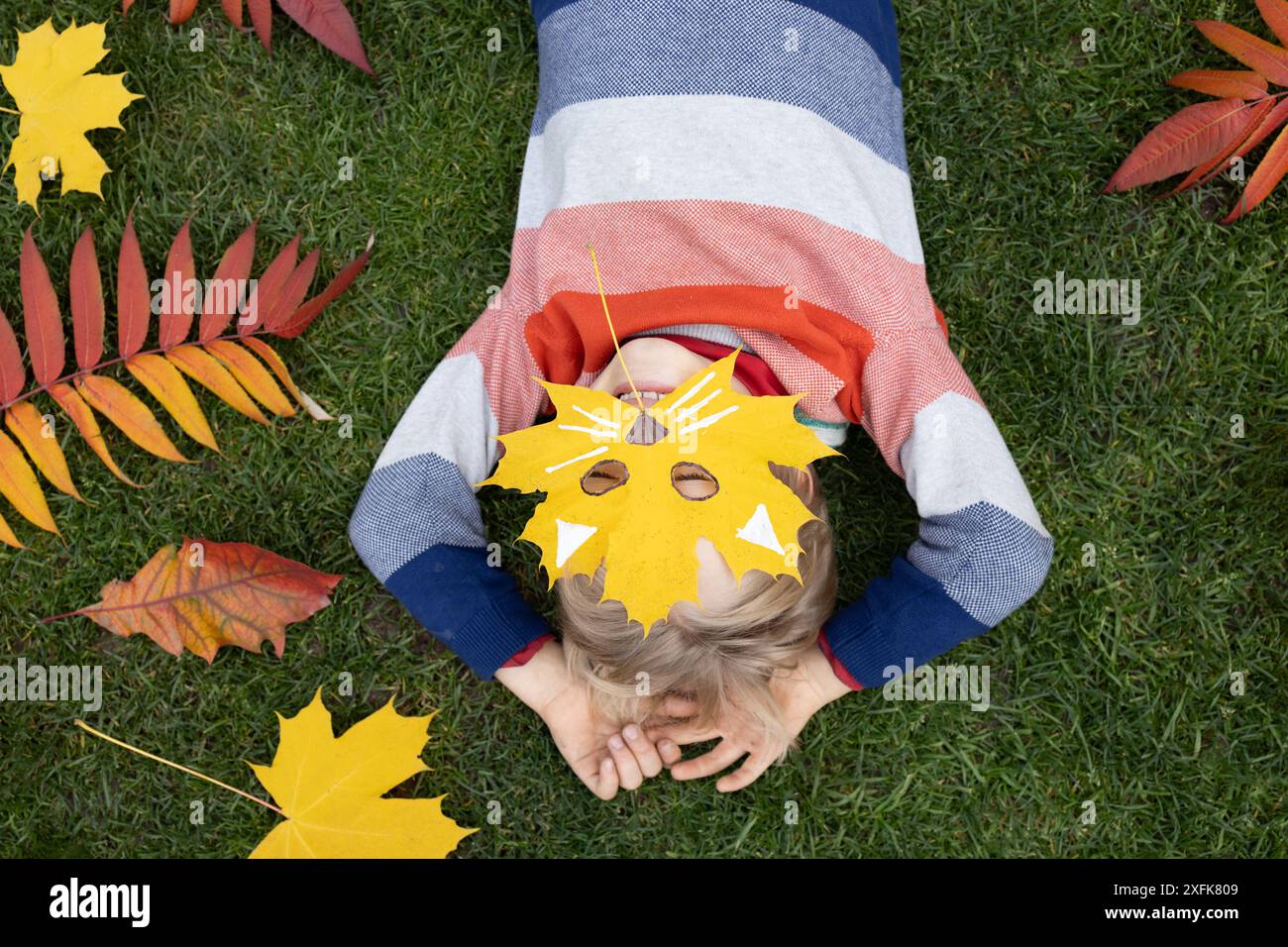 Ciao, Autunno. foto d'atmosfera stagionale. ama l'autunno e idee interessanti per la creatività. il bambino giace sull'erba e si nasconde dietro un Foto Stock