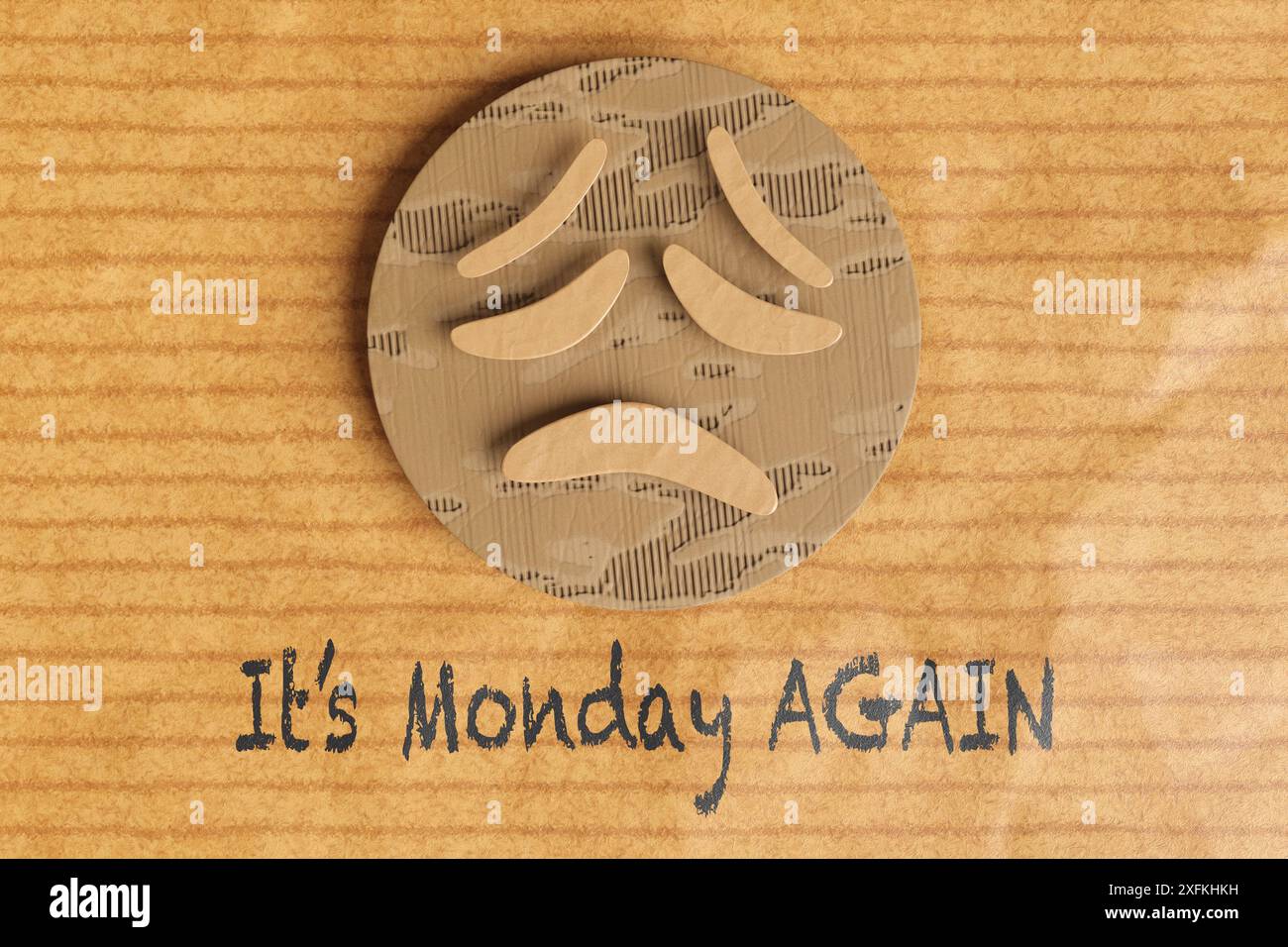 Carta che taglia il cartone di una triste faccia di emoji sgelata su una carta da imballaggio marrone con la frase "IT's Monday AGAIN" (è lunedì DI NUOVO). Sindrome di Monday Blues Foto Stock