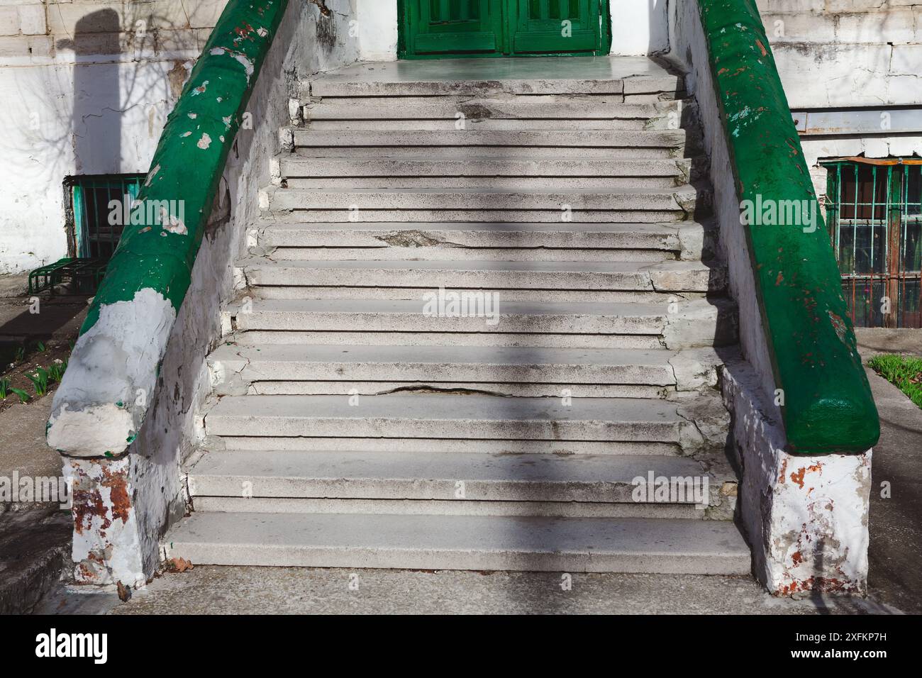 Scale d'ingresso dell'edificio abbandonato. Le scale sono verdi e bianche. I gradini sono vecchi e usurati Foto Stock