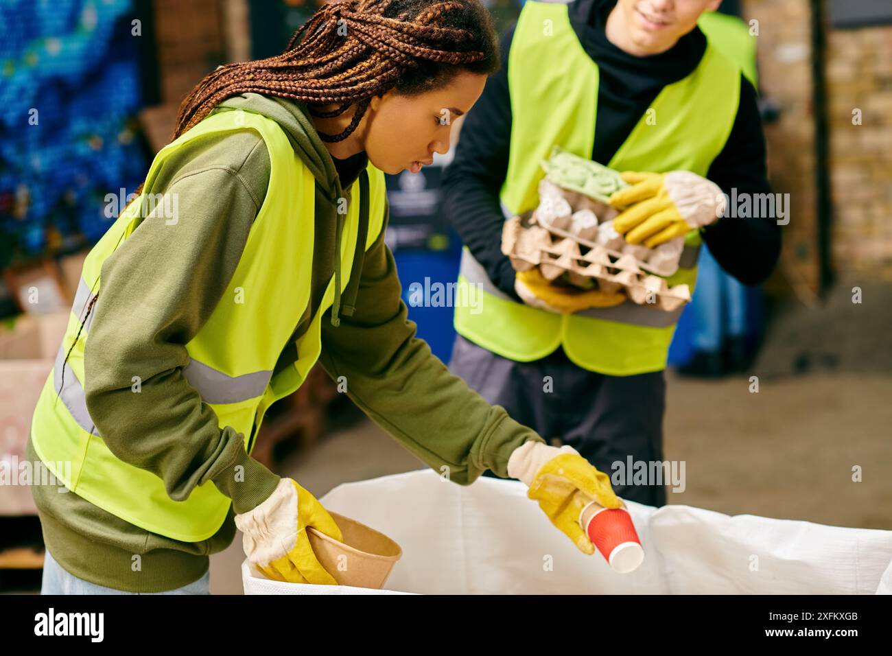 Giovani volontari in gilet verdi e gialli per lo smistamento dei rifiuti, incarnando insieme sforzi eco-consapevoli. Foto Stock