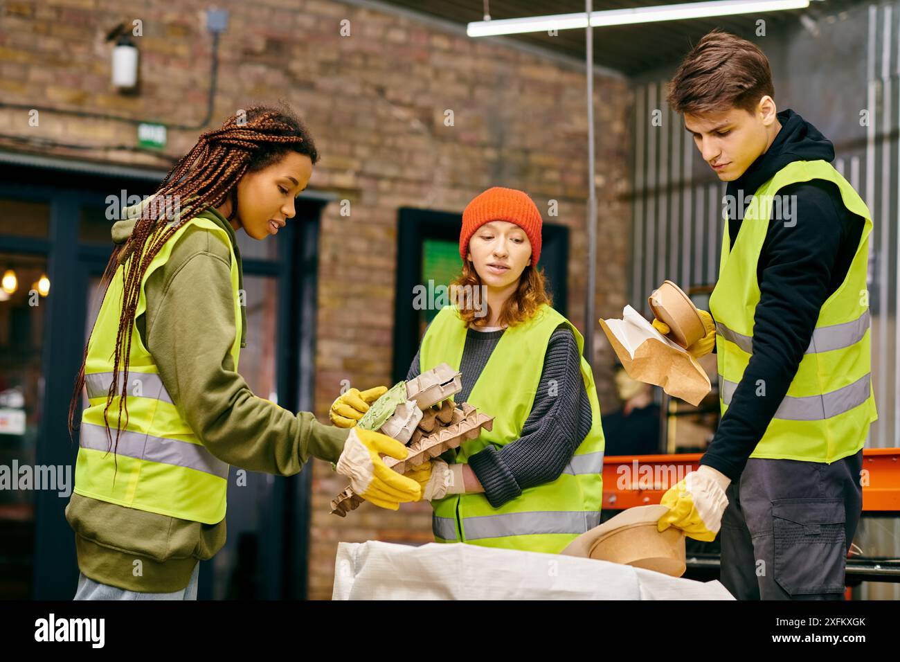 I giovani volontari in attrezzature di sicurezza collaborano per smistare i rifiuti per un futuro più verde. Foto Stock