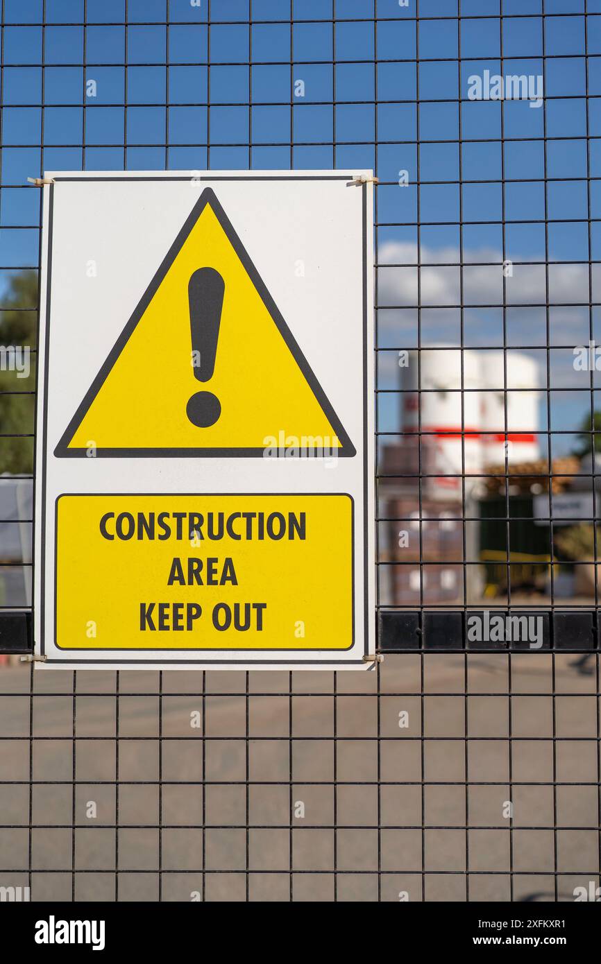 Vista ravvicinata verticale del segnale triangolare di avvertimento giallo che avvisa il pubblico: Area dei lavori tenere fuori la recinzione di sicurezza dei cavi al di fuori del cantiere del Regno Unito. Foto Stock