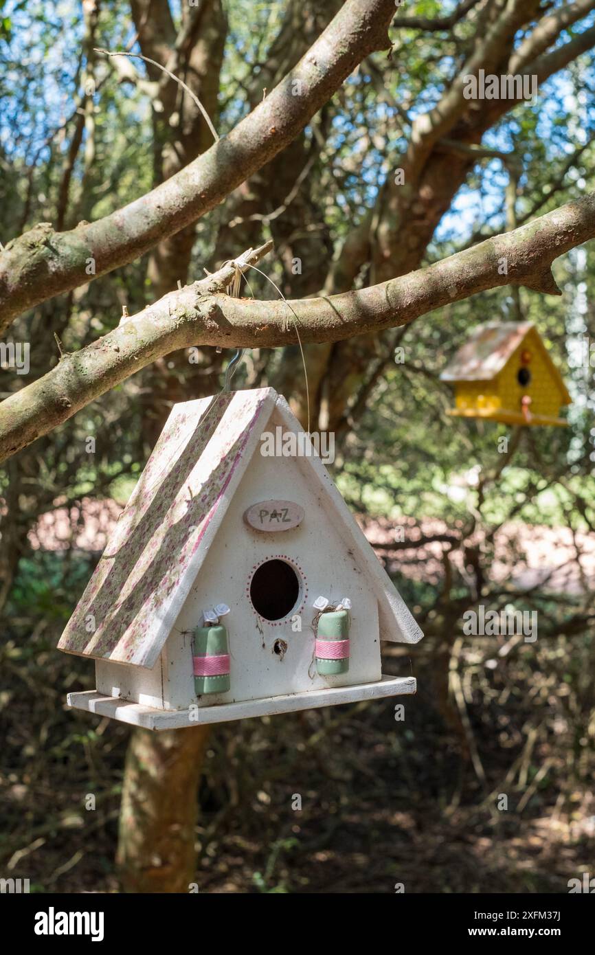 Una casa per uccelli bianca con un nastro rosa appeso ad essa Foto Stock