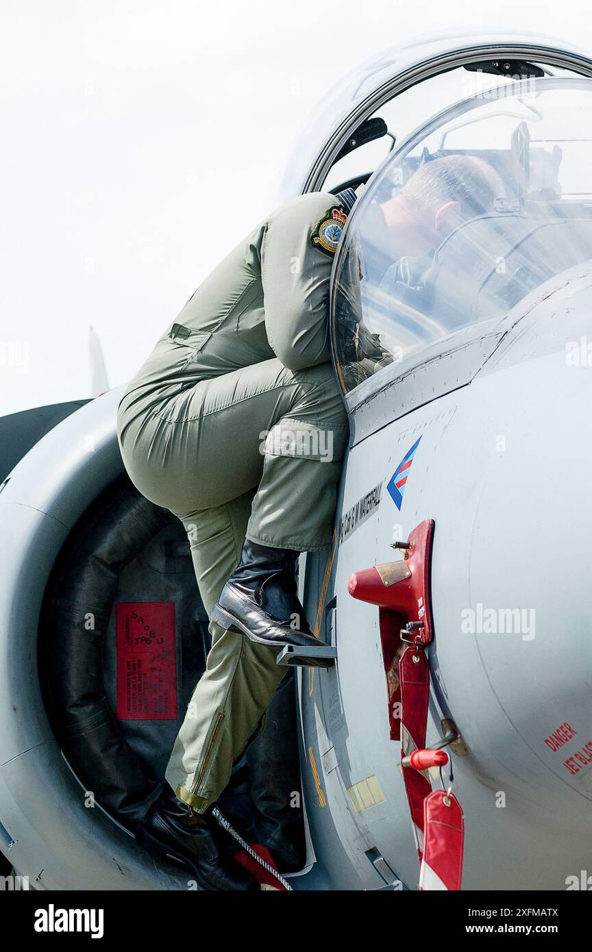 Il membro dell'equipaggio si arrampica sul jet di salto Harrier del Wing Commander GM Waterfall parcheggiato nell'area di esposizione statica al RAF Waddington Airshow 2005 Foto Stock