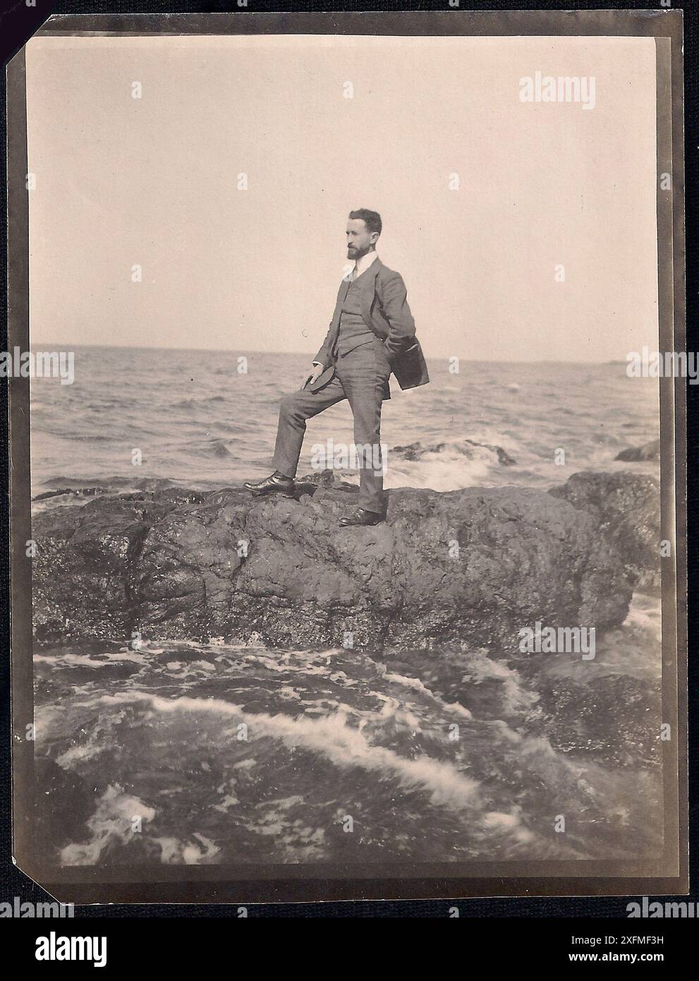 Immagine vintage di un uomo in piedi da solo su rocce in mezzo al mare (1920?) Foto Stock