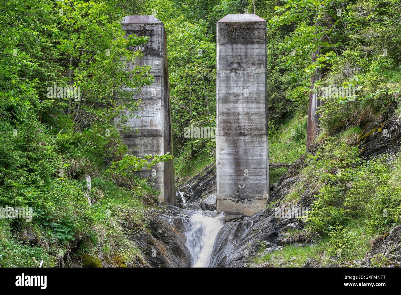 Enormi pilastri di cemento sorgono da un torrente di montagna nelle Alpi austriache. Questi "demolitori a frantumazione" proteggono gli abitanti della valle da pericolose scivoli di fango. Foto Stock